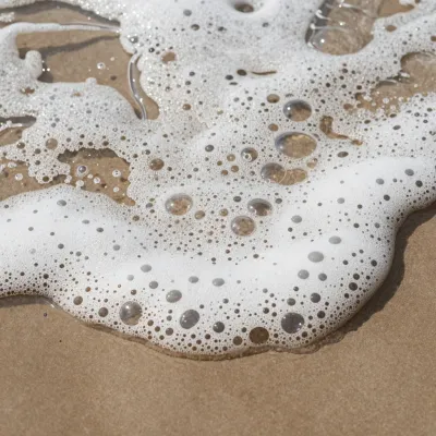 Ocean Foam on Sandy Shore - Nature - AI generated image