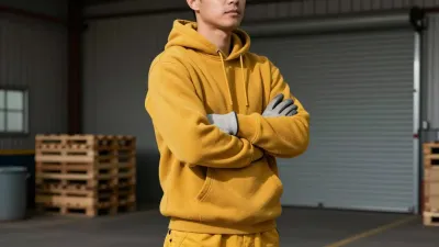 Person in Yellow Hoodie Arms Crossed in Warehouse - People - AI generated image